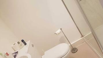 A bathroom with a white sink, toilet, and a glass shower enclosure.