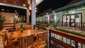 A wooden deck with a dining table and chairs, surrounded by a wooden railing. - Sari Nusa Inn (Lembongan Island)