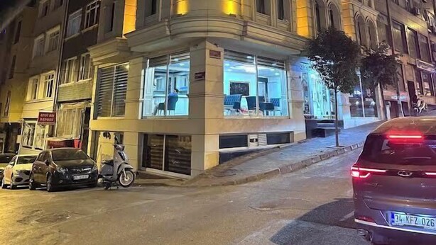 Un hotel con un llamativo letrero que dice 'ENS HOTEL', amplias ventanas y una entrada en esquina.