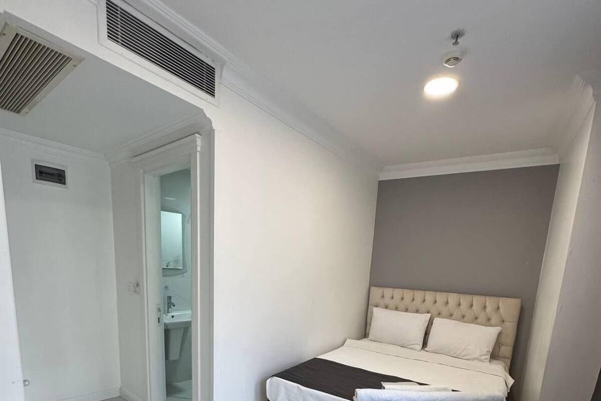 A bedroom with a bed, a desk, and a bathroom visible through an open door.