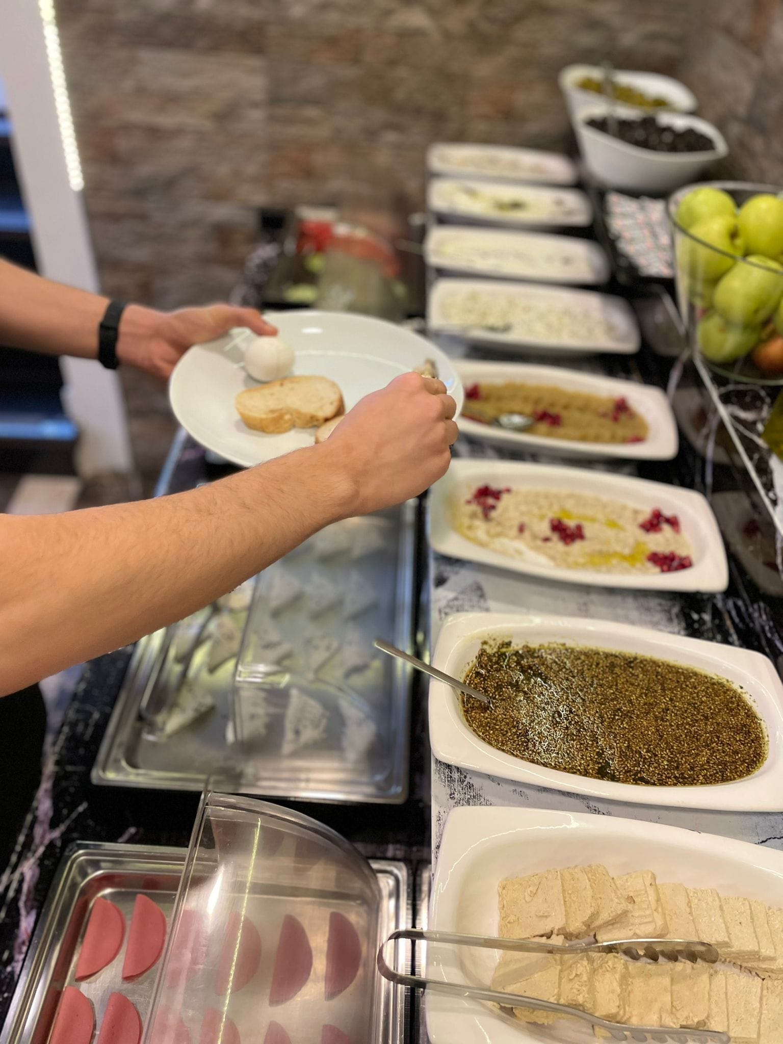A buffet setup with various dishes and a person serving food.