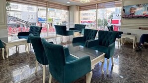 Un restaurante con piso de mármol, sillas tapizadas en verde y una mesa con cubierta de vidrio.