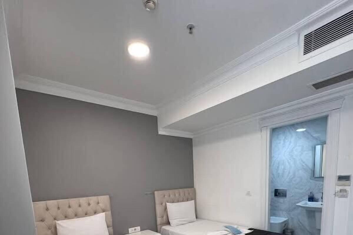 A hotel room with two beds, a small bedside table, a built-in wardrobe, and a bathroom visible through an open door.