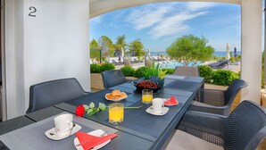 A dining table set with breakfast items, a view of the pool, and a number '2' on the wall. - Apartments Basic (Vir)