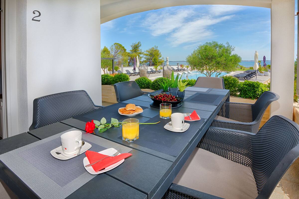 A dining table set with breakfast items, a view of the pool, and a number '2' on the wall.