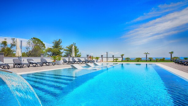 A swimming pool with lounge chairs and a waterfall feature. - Apartments Basic (Vir)