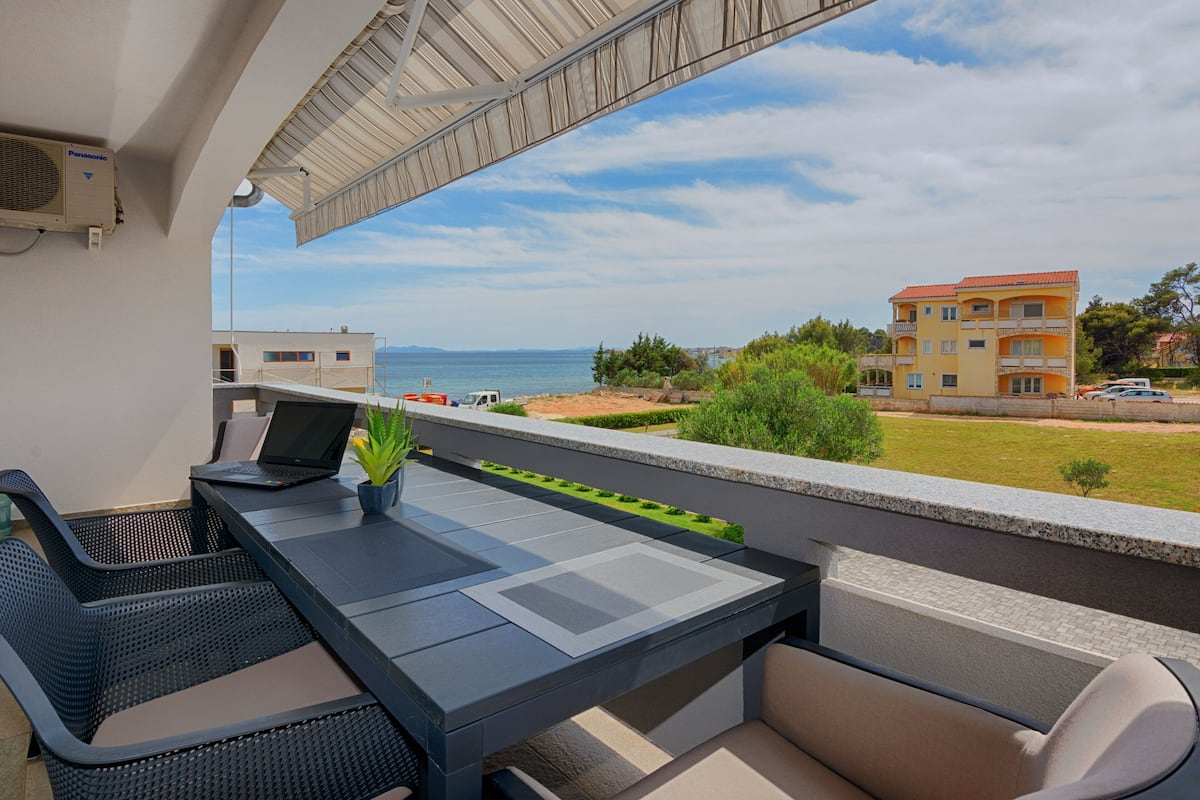 A balcony with a table, chairs, and a laptop.