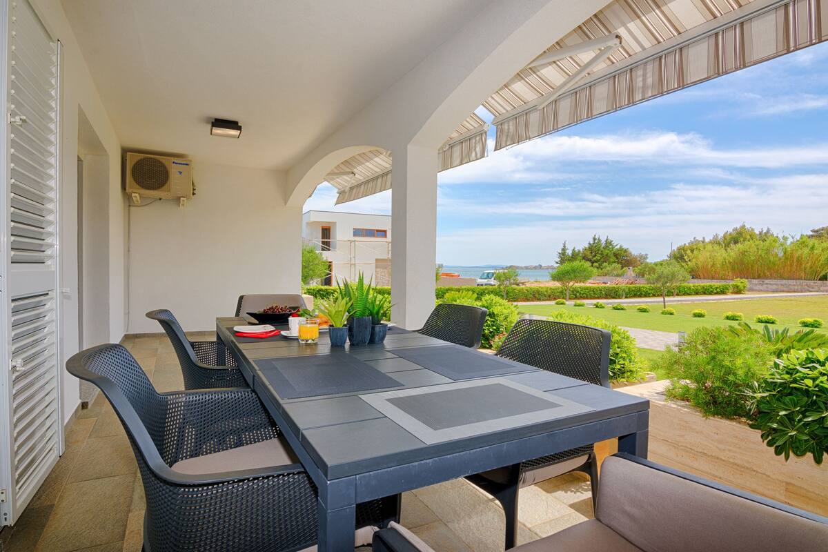 An outdoor patio with a dining table, chairs, and potted plants.