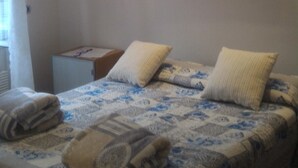 Un dormitorio con dos camas, un cuadro en la pared y un escritorio pequeño.
