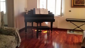 Una habitación con un piano de cola, una araña y un banquillo para piano.