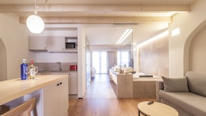 A modern kitchen with wooden flooring, a dining area with a round table, and a living room with a sofa. -  Apartahotel Fil Suites (Palma de Mallorca)