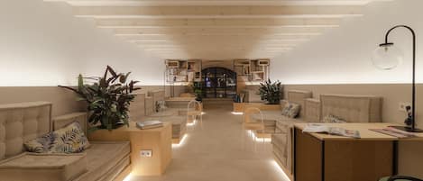 Una sala de estar moderna y bien iluminada, con una zona de estar central, estanterías empotradas y una escalera que conduce a un nivel superior.