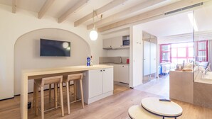 A modern kitchen with wooden beams, a TV mounted on the wall, and a dining area with stools. -  Apartahotel Fil Suites (Palma de Mallorca)