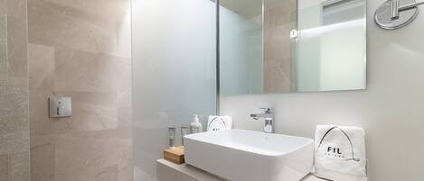 Un baño moderno con una bañera grande, cerramiento de ducha de vidrio y un espejo sobre el lavamanos.