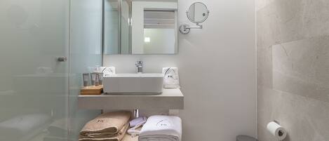 Un baño moderno con cabina de ducha de vidrio, lavamanos blanco y retrete.