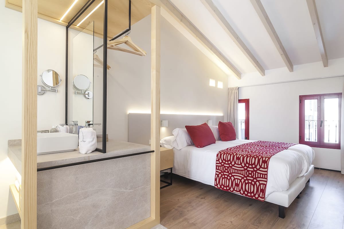 Ein modernes Schlafzimmer mit einem großen Bett, einem Nachttisch, einem Spiegel und einem Fenster mit Blick.