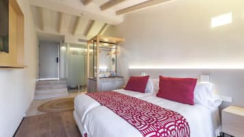 Un dormitorio moderno con una cama grande, ropa de cama roja y blanca, una mesita de noche y un cabecero integrado.
