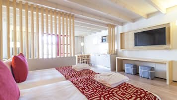 Hotellihuone, jossa on suuri sänky, seinälle asennettu televisio ja työpöytä tuolilla.