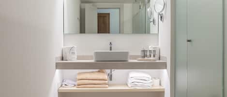 A modern bathroom with a large mirror, a sink, and a towel rack.