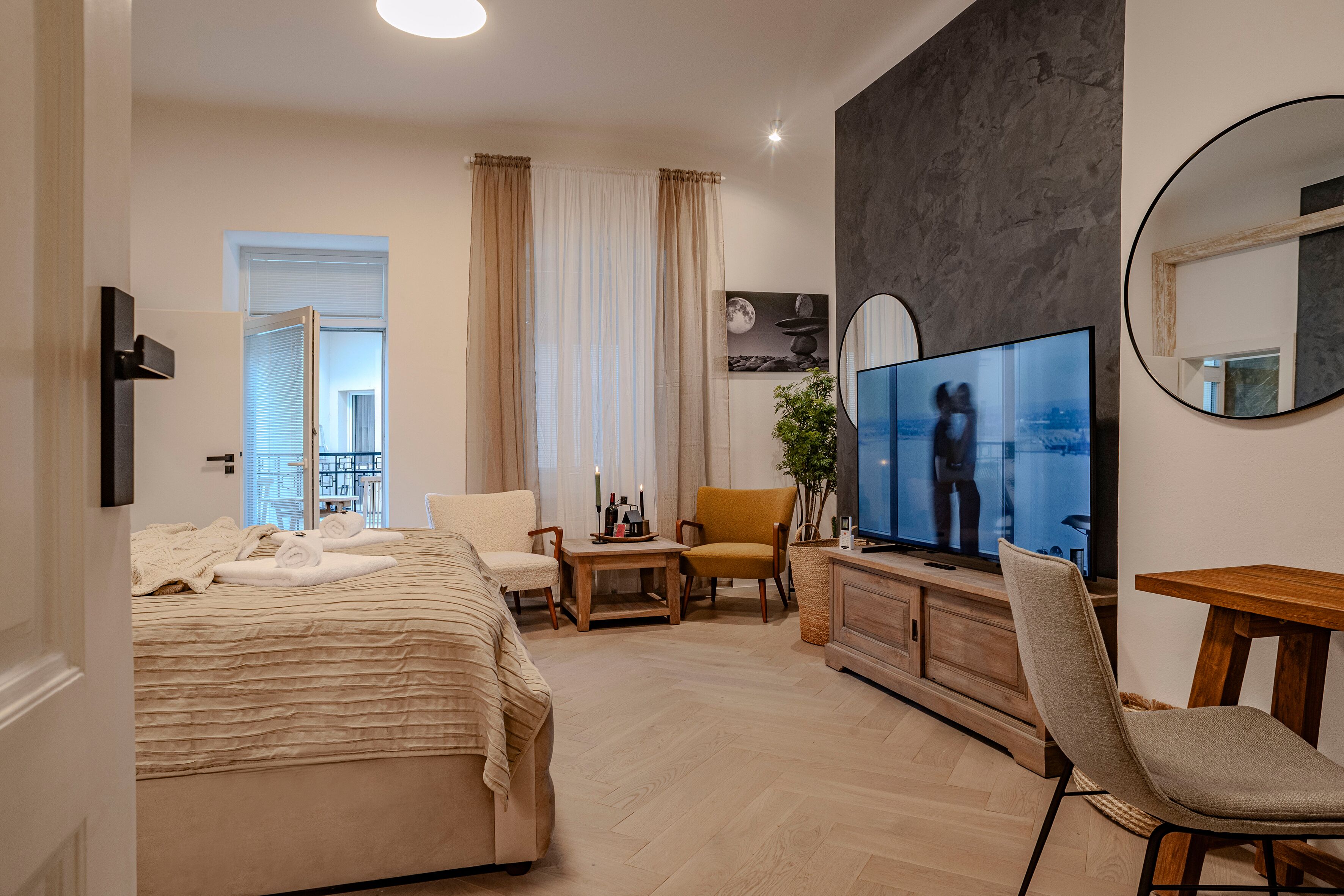 Una habitación de hotel moderna con cama, televisión, zona de estar y balcón.