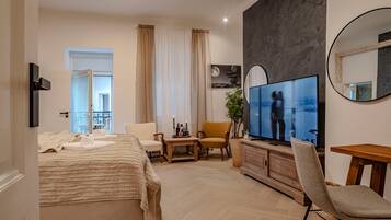 Una habitación de hotel moderna con cama, televisión, zona de estar y balcón.