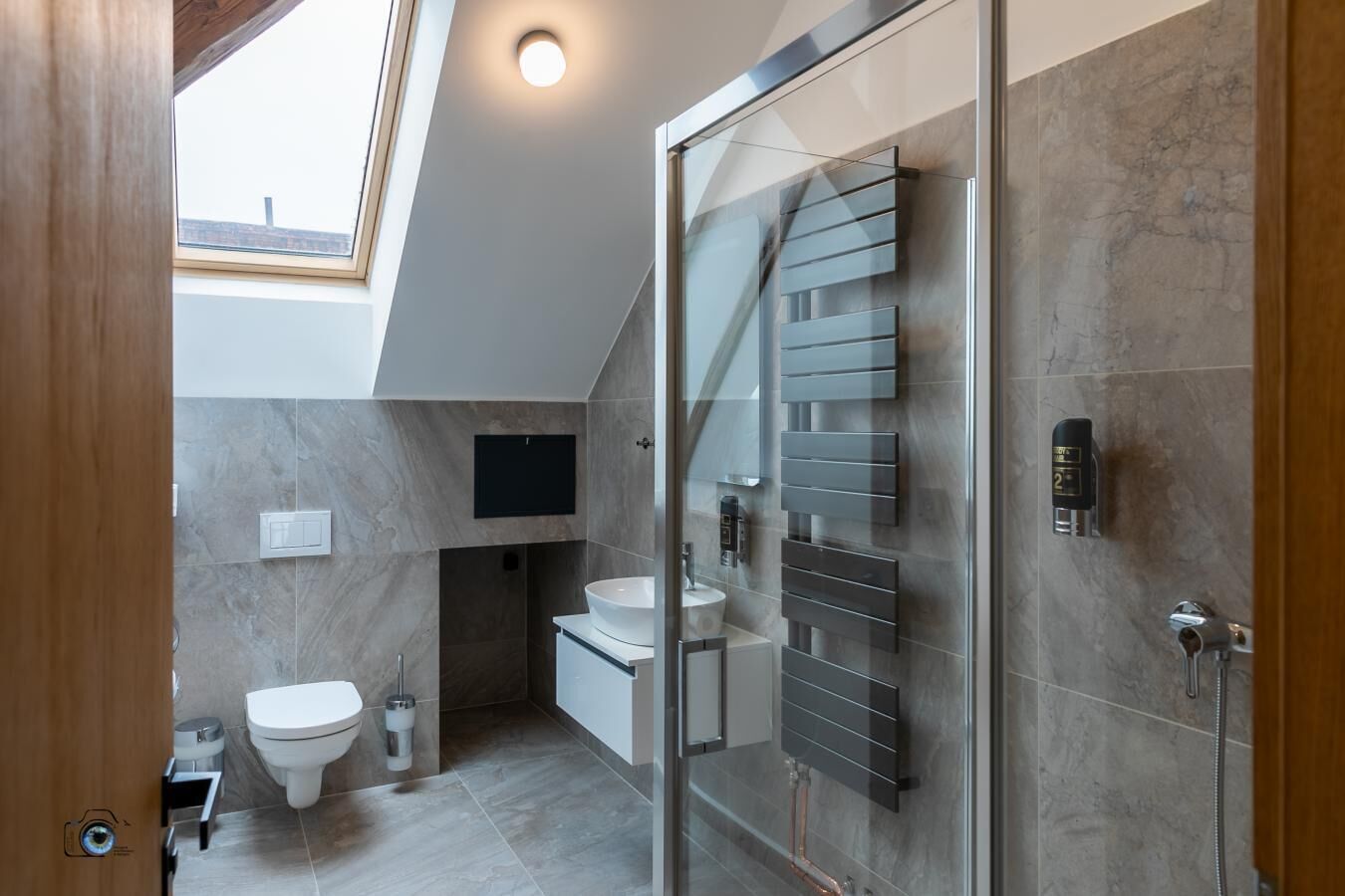 Ein modernes Badezimmer mit Oberlicht, Duschkabine aus Glas, Waschbecken und Toilette.