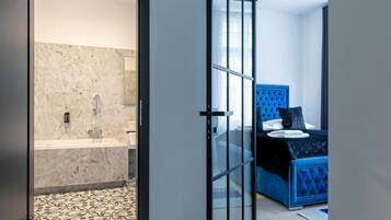 A modern bathroom with a marble wall and a patterned floor.