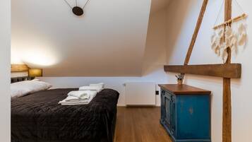 A bedroom with a bed, a nightstand, a dresser, and a wall-mounted macrame piece.