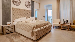 Un dormitorio amplio con una cama grande, una mesita de noche, una silla y una pequeña mesa con una vela.