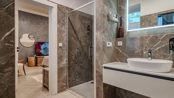 A modern bathroom with a glass-enclosed shower, a white sink, and a large mirror.