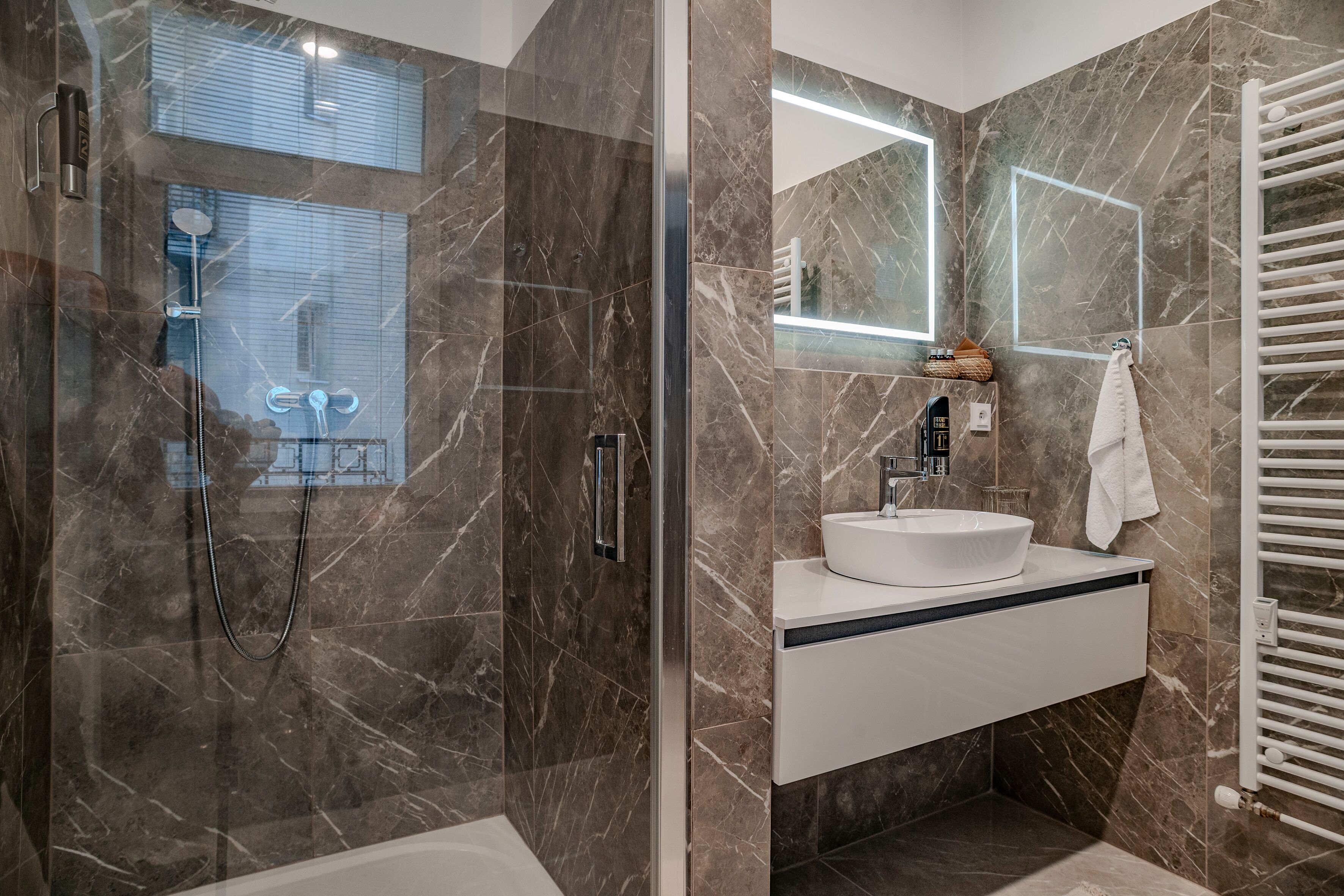 Une salle de bain moderne avec une douche à parois de verre, un lavabo blanc et un grand miroir.