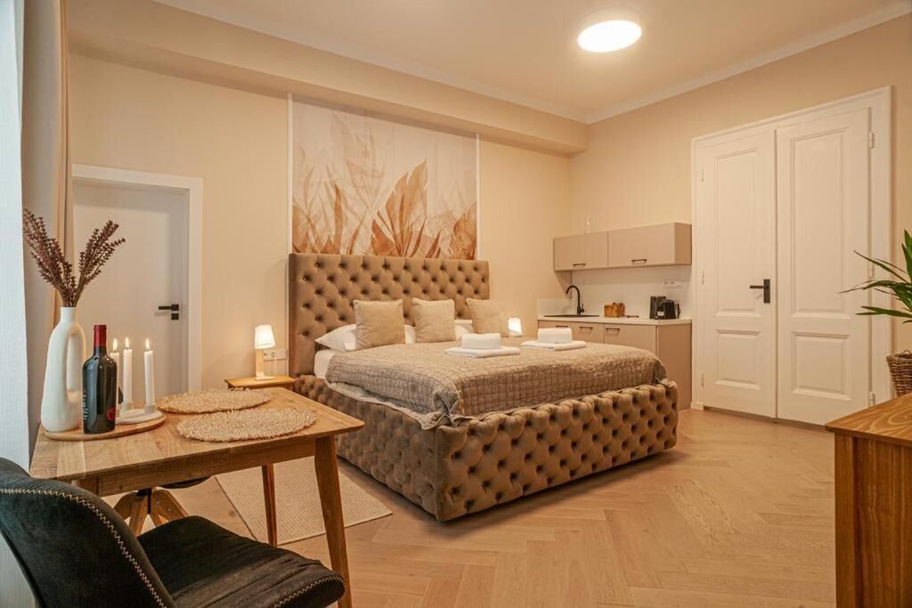 Une chambre à coucher avec une tête de lit capitonnée, une table de chevet avec des bougies, une lampe et un vase décoratif.