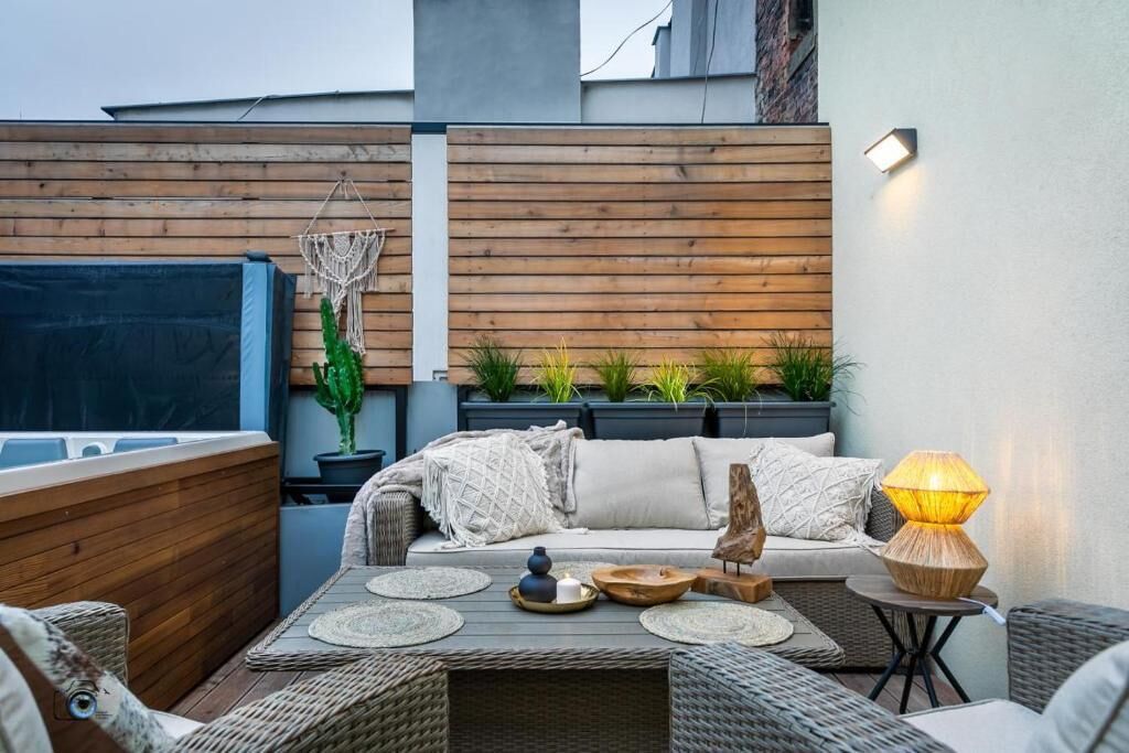A cozy outdoor seating area with a sofa, cushions, and a table set with decorative items.