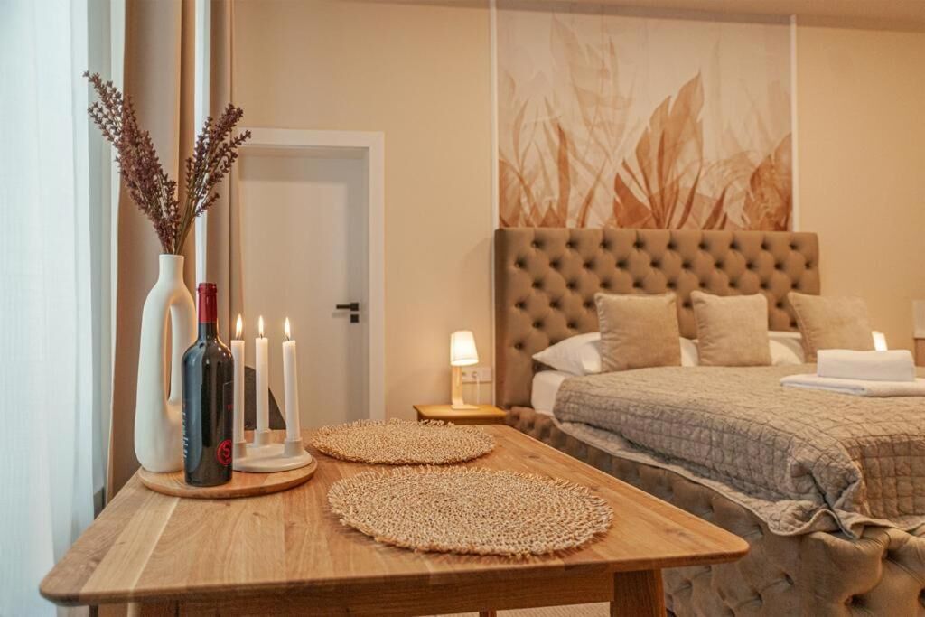 A bedroom with a tufted headboard, a bedside table with candles, and a vase with dried flowers.