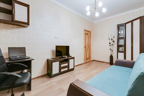 Relax in this cozy space with a flat-screen TV, comfortable sofa, and wooden wardrobe.