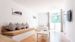 A modern living room with a sofa, a coffee table, and a television. - Neighbours Apartments (Calvia)