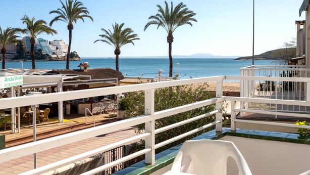 A seaside view with a restaurant named "Ancla Verde" and a white railing overlooking the beach. - Neighbours Apartments (Calvia)