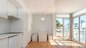 A modern kitchen with white cabinetry, a built-in dishwasher, and a large window offering a view of palm trees and buildings. - Neighbours Apartments (Calvia)