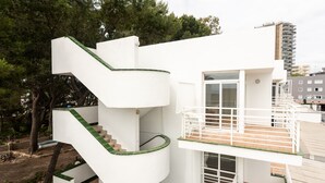 A modern multi-story building with a white exterior, a spiral staircase, and a balcony with a railing. - Neighbours Apartments (Calvia)