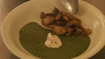 Dos tazones de sopa verde con una cucharada de crema y comida frita al lado.