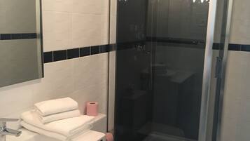Uma casa de banho moderna com lavatório branco, sanita e cabine de duche com parede de vidro.
