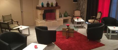 A modern living room with a fireplace, comfortable seating, and a red carpet.