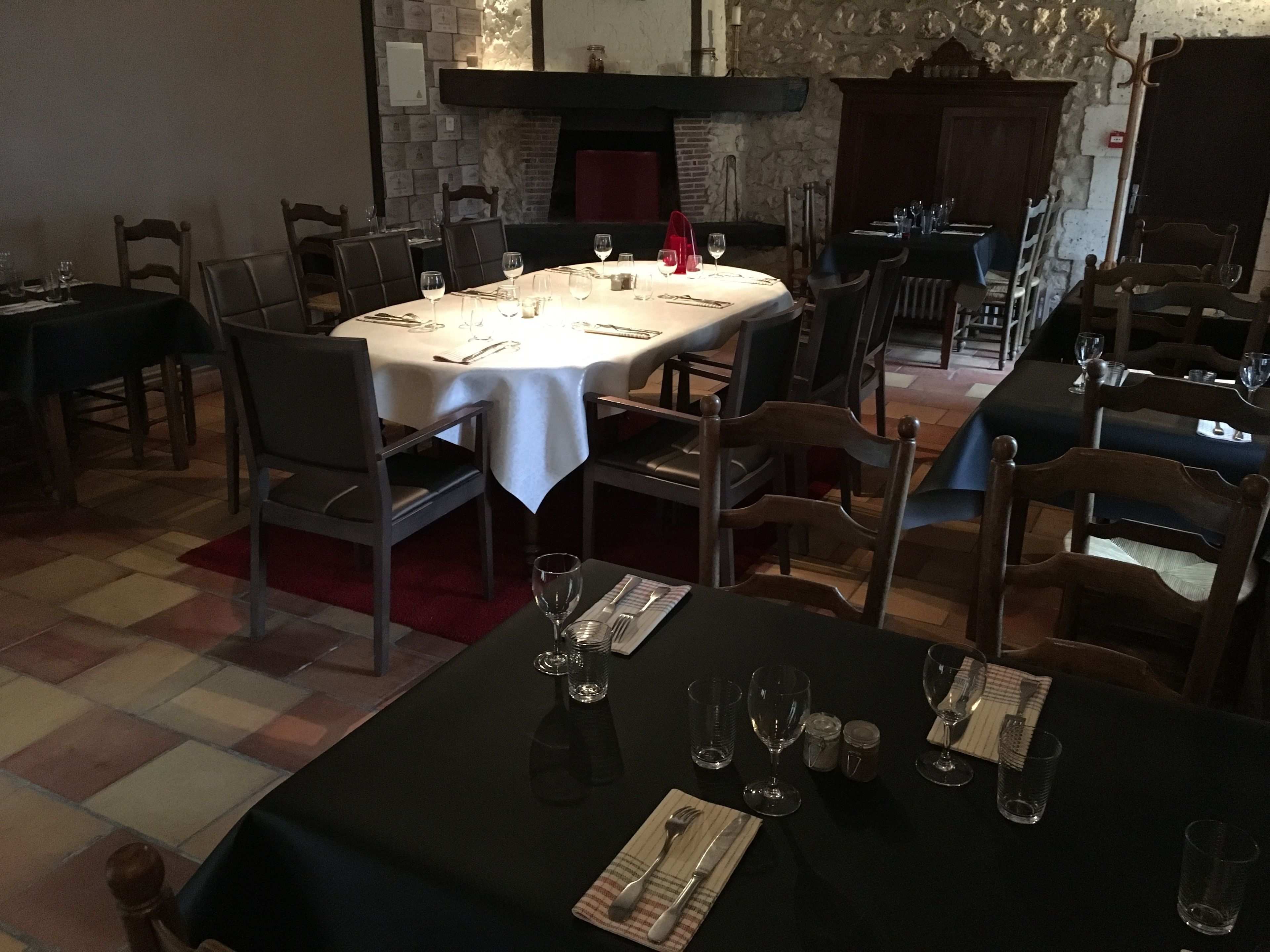 Un restaurante con mesas redondas dispuestas para comer, sillas alrededor de cada mesa y una pared de piedra al fondo.