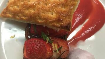 Un piattino con un dolce, fragole e una pallina di gelato.