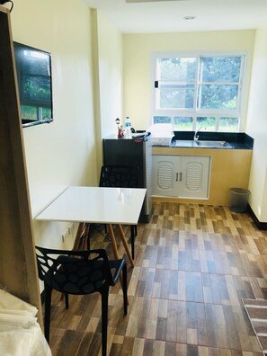 Cocina pequeña con ventana, un lavamanos y una mesa con sillas.