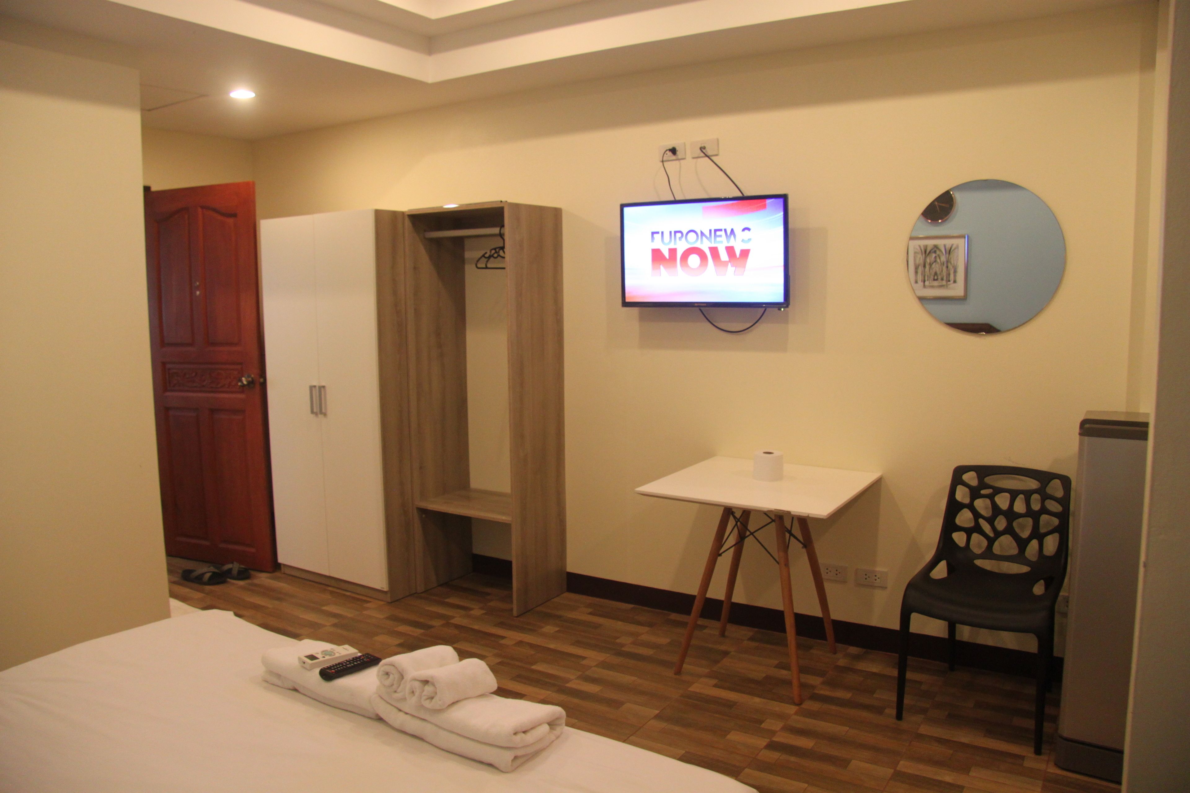 Habitación de hotel con cama, televisión, una mesita, una silla y armario.