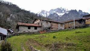 Ein rustikales Steinhaus mit traditionellem Satteldach, gelegen in einer Bergregion, wobei ein klarer Weg daraufhin führt.