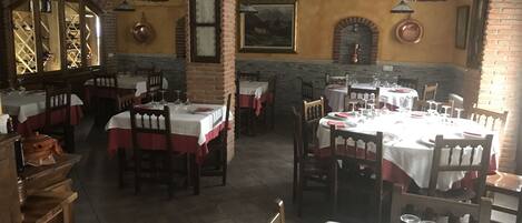 A restaurant with brick walls, white tablecloths, and wooden chairs.