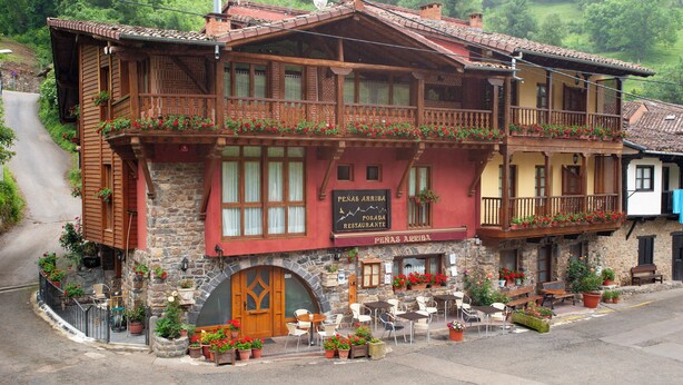 Ein traditionelles Holzhaus mit Balkonen, einer Stein-Fassade und Außenplätzen.