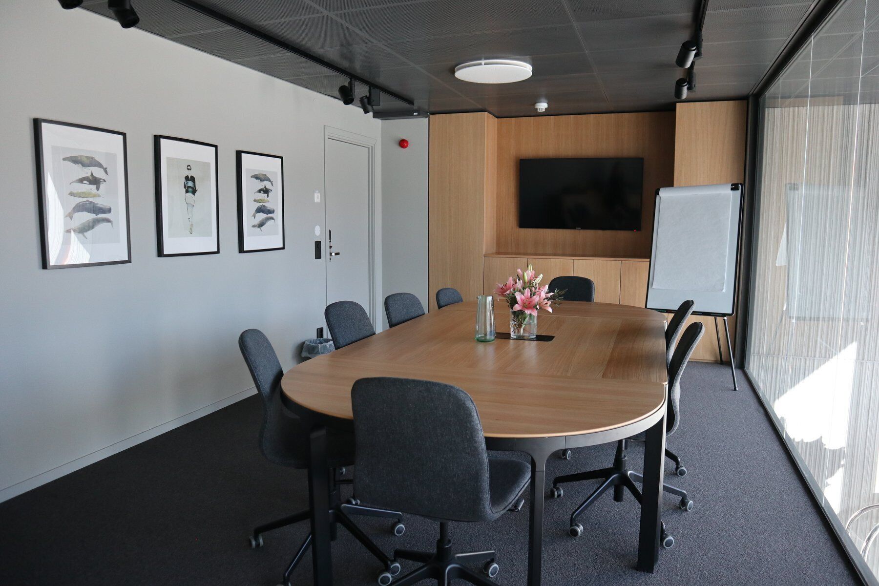 Une salle de conférence équipée d’une grande table, de chaises, d’un tableau blanc et de tableaux encadrés accrochés au mur.